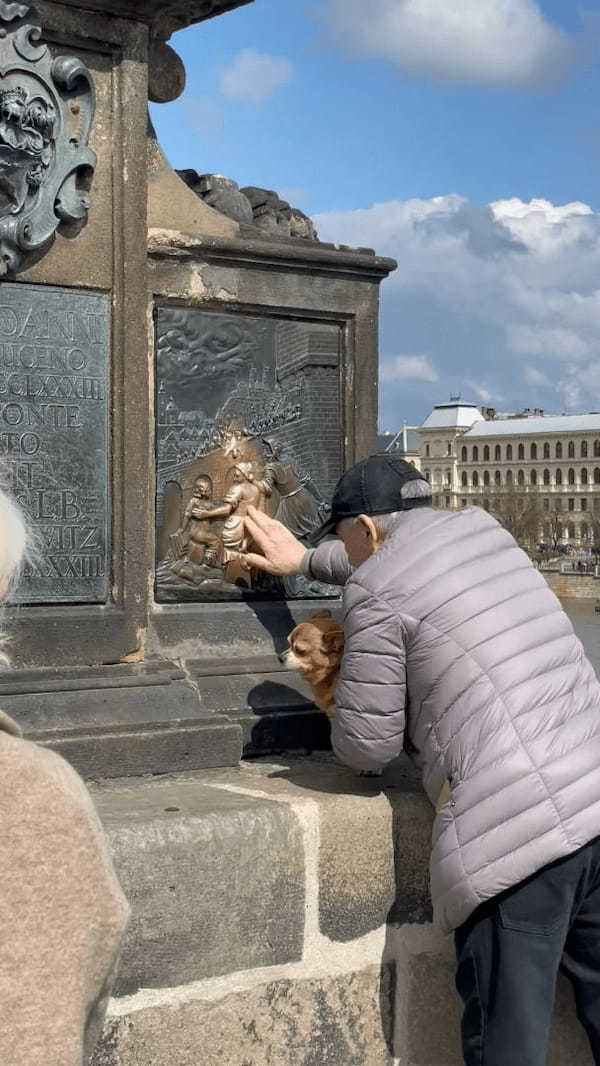 プラハの観光地で目撃された微笑ましい光景。撫でると願いが叶うとされるプレートを、おじいさんが愛犬にもナデナデさせていました！