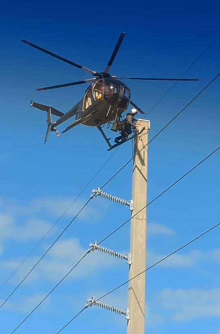 道路の上空でヘリコプターがホバリングしていると思ったら・・・、なんと機体を足場にして電線のメンテナンスをしている人がいたのです！！