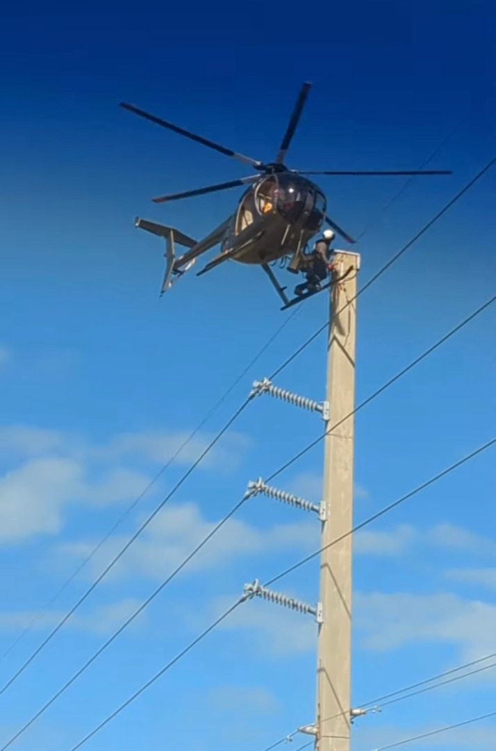 道路の上空でヘリコプターがホバリングしていると思ったら・・・、なんと機体を足場にして電線のメンテナンスをしている人がいたのです！！