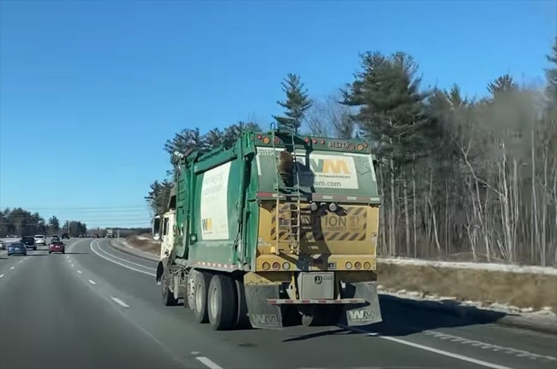 高速道路を走行中に出くわしたまさかの光景。目の前を走るゴミ収集車の後ろには意外すぎる『珍客』の姿が！